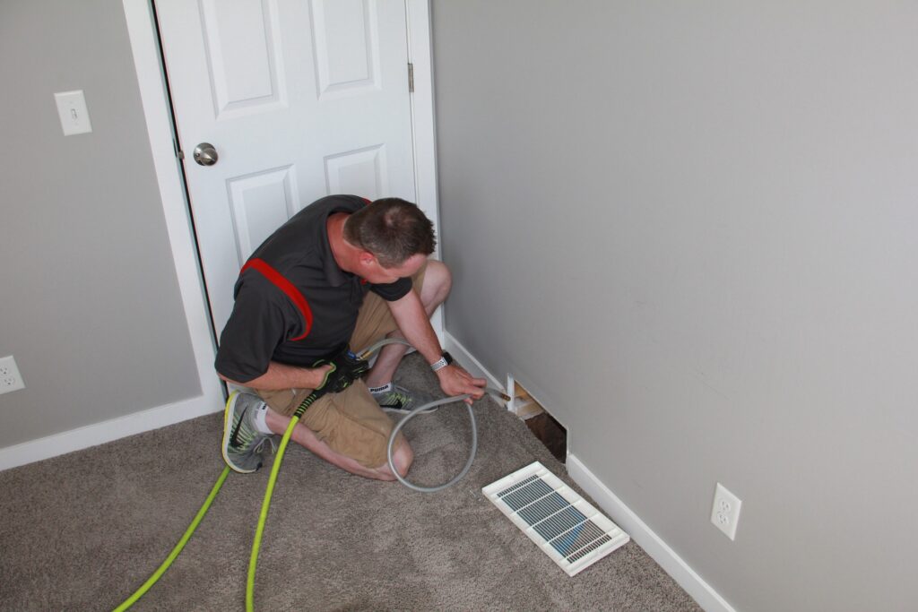 man cleaning a duct vent to remove the dust