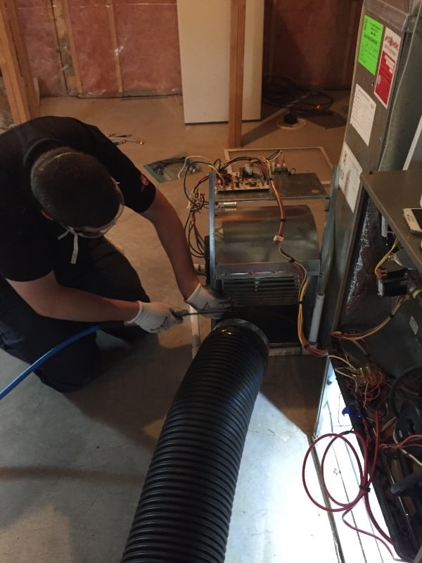 man cleaning the furnace to remove dust